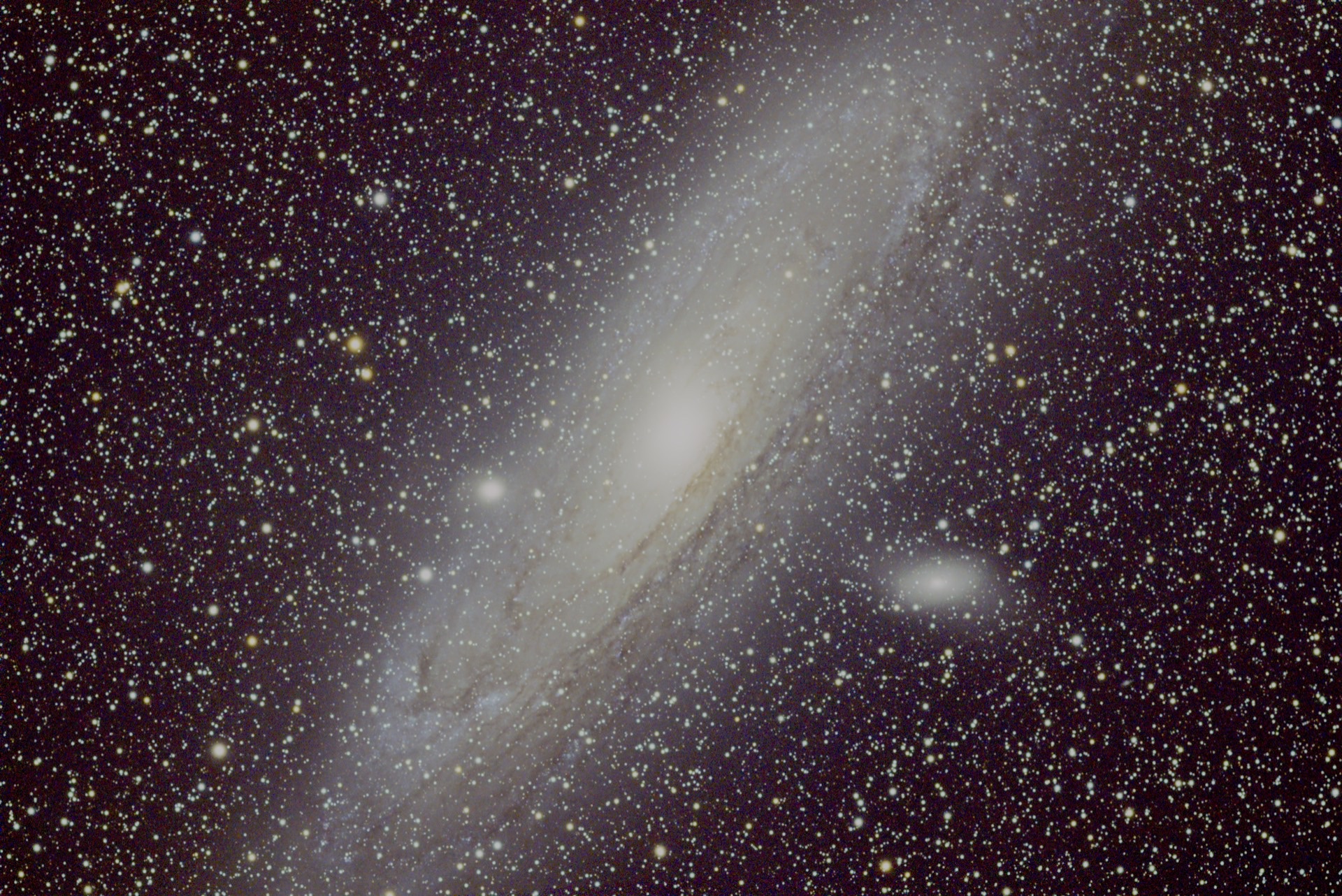 The Andromeda Galaxy, a tilted spiral with a bright core, dust lanes, and the companion galaxy M110.